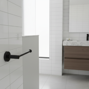 Bathroom with white tiled walls, wooden vanity, and black grab bar.